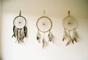 Trois attrape-rêves de styles distincts alignés sur un mur clair : bohème à longues franges, minimaliste à cerceau nu, et traditionnel